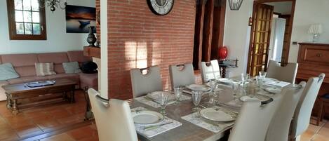 A dining area with a brick wall, a large clock, and a chandelier.