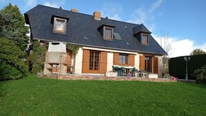 Une maison à deux étages, avec un toit sombre, de grandes fenêtres et une pelouse bien entretenue.