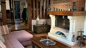 Un salon avec une cheminée en briques, une table basse en bois et un canapé rose.