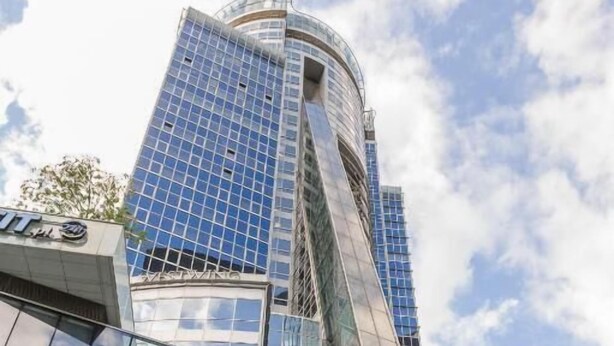A modern building with a glass facade and a unique angular design. - Comfortable studio on Twarda in Center (Warszawa)
