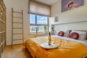 A bedroom with a bed, a window, a ladder, and a bottle of wine on a tray.