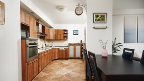 Uma cozinha moderna com armários de madeira, forno embutido e um espaço de refeições com mesa e cadeiras.