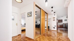Um corredor com piso de madeira, porta deslizante e iluminação pendente.