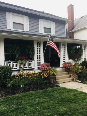 Stroll up to this charming home, featuring a welcoming porch, a brick chimney, and a beautifully manicured lawn.