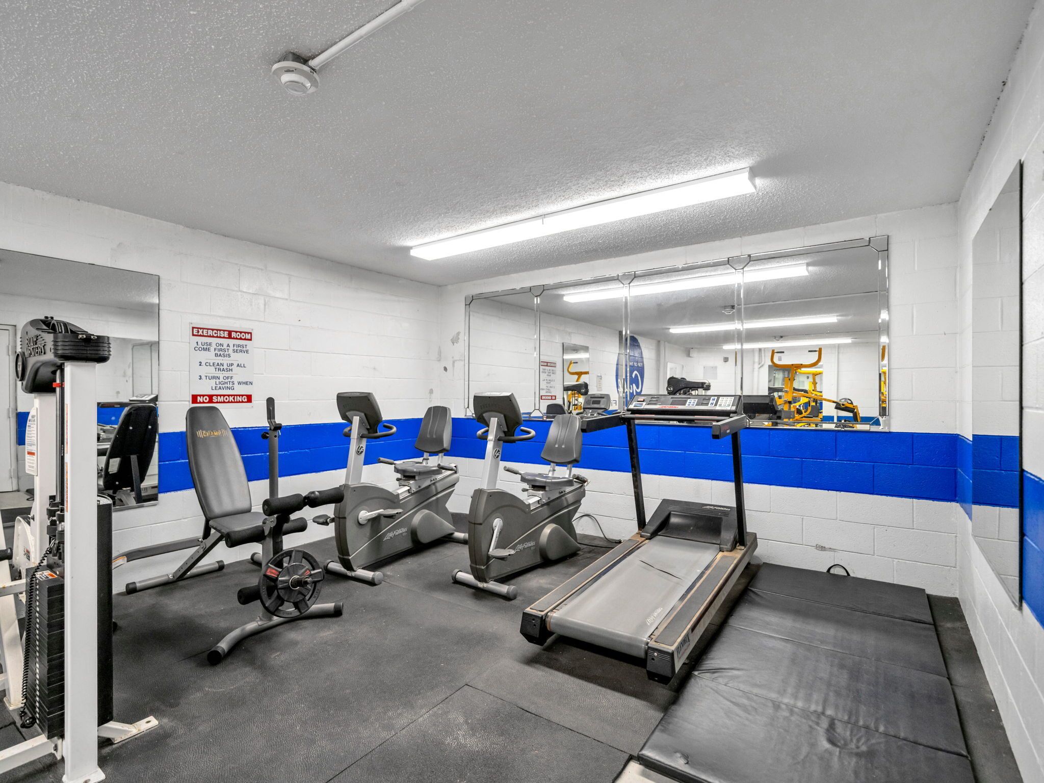 A gym with exercise equipment, a treadmill, and a mirror.