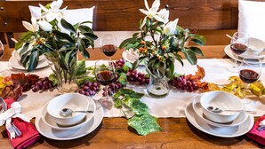 A dining table set with white plates, bowls, and glasses, adorned with flowers and grapes. - A spacius and comfortable apartment with a large terrace (Toscana)
