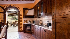 A kitchen with wooden cabinets, a stove, and a sink. - A spacius and comfortable apartment with a large terrace (Toscana)