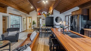 Un vaste espace de vie doté d’un plafond en bois, d’une grande table à manger et d’une cuisine équipée d’appareils électroménagers modernes.