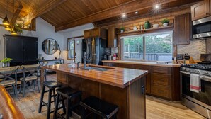 Une cuisine moderne avec des meubles en bois, des appareils en acier inoxydable et un grand îlot central doté de tabourets.