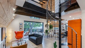 Un intérieur moderne avec un escalier, un coin salon et une vue sur l’extérieur.