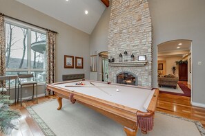 Relax in the spacious living room with a pool table, stone fireplace, and comfortable seating area.