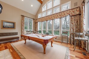 Relax in a spacious room with a pool table, comfortable seating area, and decorative artwork.