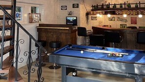 Une pièce de style loft avec une table de billard, un coin bar et un escalier.