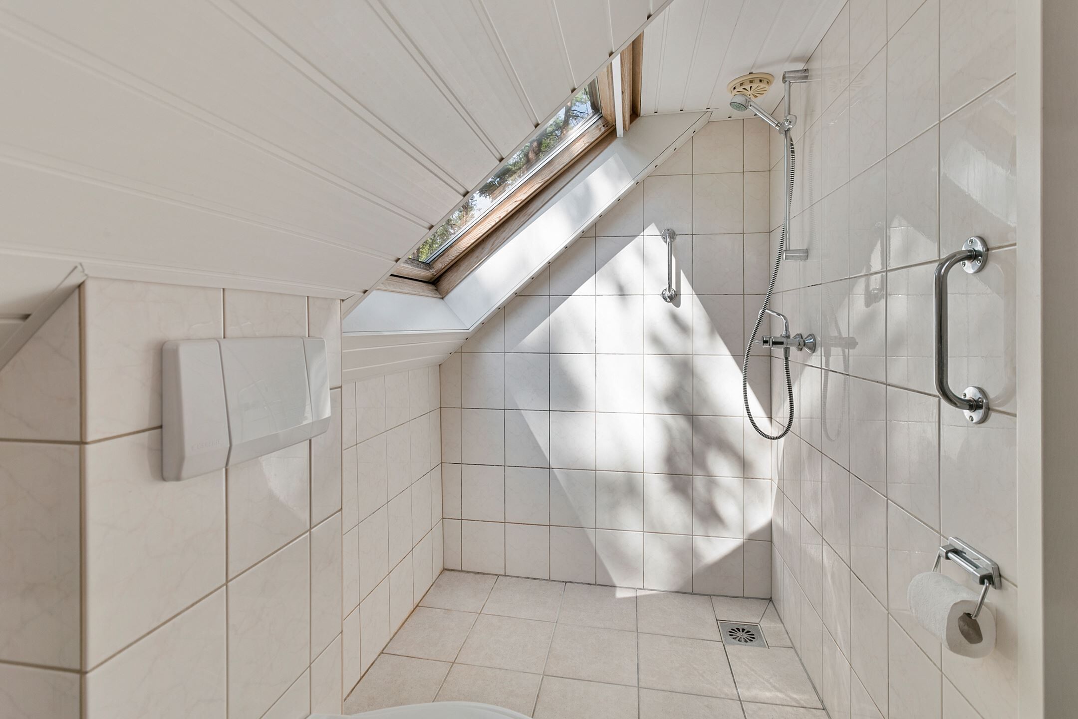 Ein kleines Badezimmer mit Fliesen, einer Dusche, einer Toilette und einem Fenster.