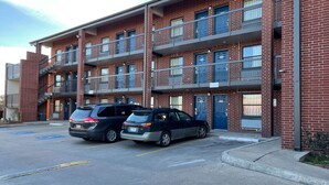 Un immeuble en briques à plusieurs étages, doté de balcons et d’un parking.