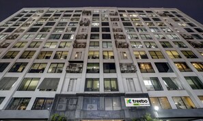 Un hotel de varios pisos con un diseño moderno, que cuenta con balcones en cada planta y un letrero llamativo que dice 'Treebo Castle Rock Inn'.