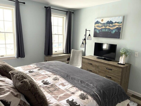 Un dormitorio con cama, cómoda, televisor y un cuadro en la pared.