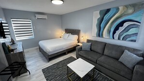 Une chambre à coucher moderne avec un lit, un canapé, une table basse et un tableau au mur.