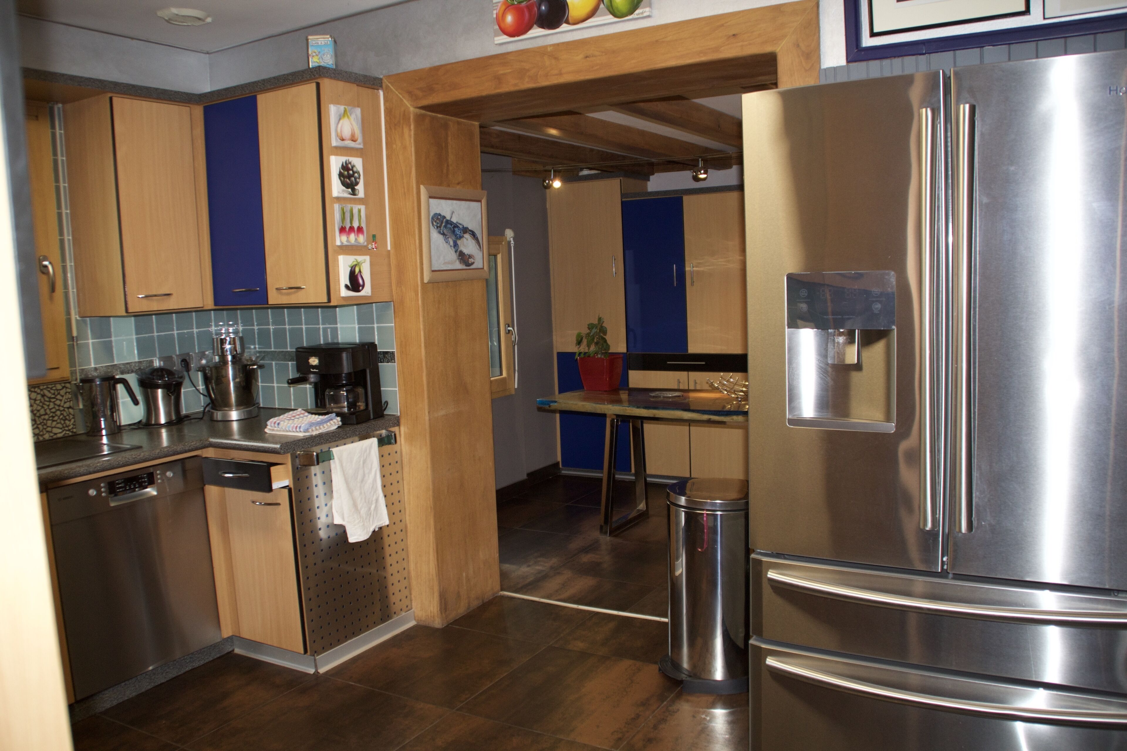 A modern kitchen with wooden cabinets, a stainless steel refrigerator, and a coffee maker.
