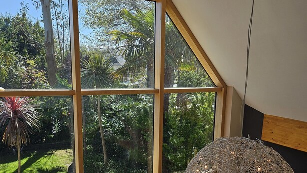 A room with large windows offering a view of a garden, a spherical decorative light fixture, and various small sculptures on a table. - Villa indoor pool, hamman, sauna, jacuzzi, gym, billiards, baby (Plouezoc'h)