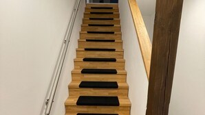 A modern staircase with wooden steps and black risers, leading to a landing. - New vacation apartment with roof terrace (Bünsdorf)