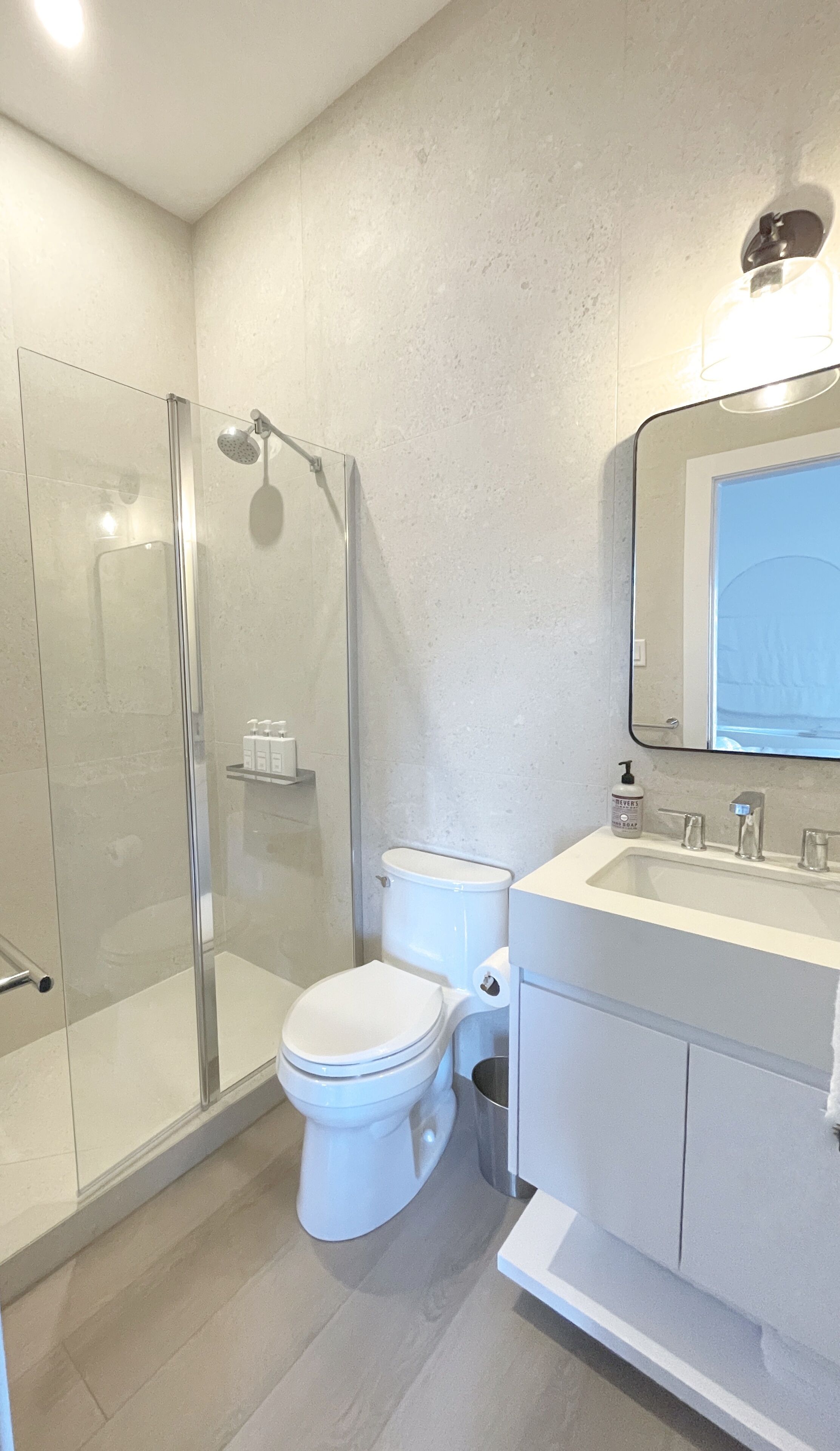 Un bagno moderno con doccia vetrata, un water e un lavabo con specchio.