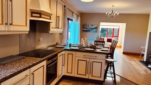 Een moderne keuken met granieten werkbladen, een inbouwoven en een eethoek met een tafel en stoelen.