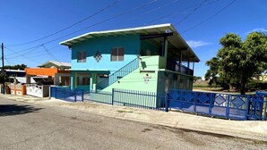 Un edificio de dos pisos con fachada azul y una escalera que conduce al nivel superior.