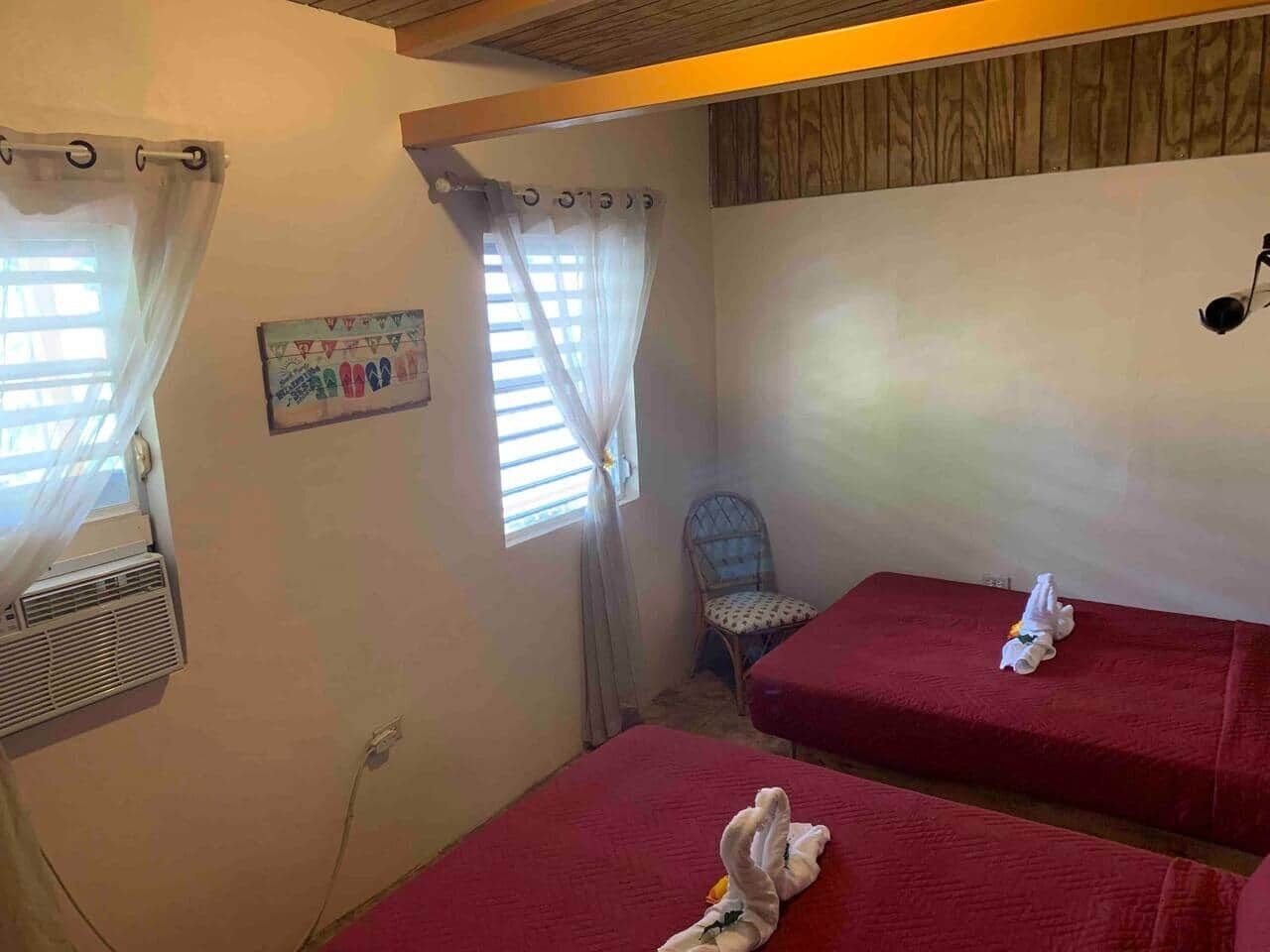 A small room with two beds, a chair, and a window with curtains.