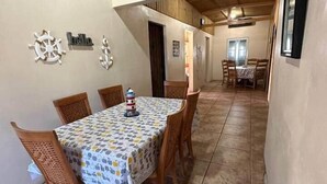 Un comedor con una mesa dispuesta para cuatro personas, sillas de madera y un mantel estampado.