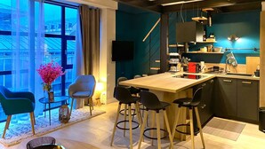 A modern kitchen with a wooden island, bar stools, and a large window with curtains.