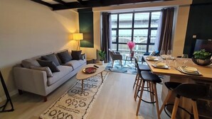A modern living room with a sofa, coffee table, and dining area with chairs and a table set for a meal.