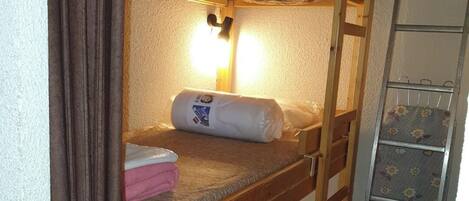 Un lit superposé avec une échelle et une étagère décorée d’un motif floral.