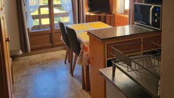 A kitchen with a microwave, a dining table with chairs, and a sliding glass door leading to an outdoor area.