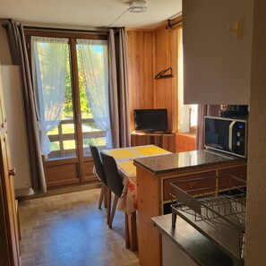 Een keuken met een magnetron, een eettafel met stoelen en een schuifdeur naar een buitenruimte.
