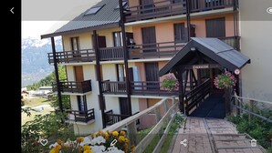 Ein mehrstöckiges Hotel mit Balkonen, einem überdachten Eingang und Blick auf Berge.