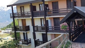 Un edificio de varios pisos con balcones, una escalera y un cartel que dice 'EMERAUDE'.
