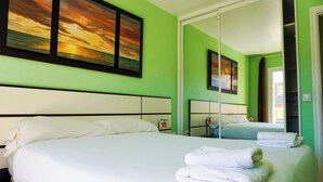 A hotel room with a large bed, two bedside tables, and a mirror. - South Coast Apartment (Puertito de Güímar)