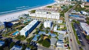 Vista aérea de una zona costera con playa, un hotel de varios pisos y una autopista cercana.