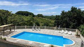 A rectangular swimming pool with a curved edge, surrounded by a stone deck and a low stone wall.