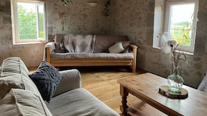 A rustic room with a wooden sofa, a wooden table, and a stone wall.
