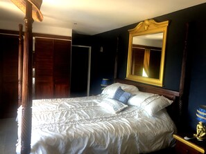 A bedroom with a large bed, a wooden headboard, a mirror, and a nightstand with a lamp. - Immaculate 1-bed Apartment on Ocean View (Philipsburg)
