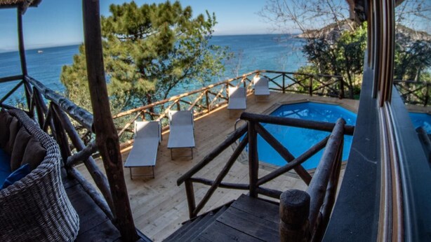 A wooden deck with lounge chairs overlooking a pool and the sea. - Villa Ad Maiora in Massa Lubrense (Massa Lubrense)