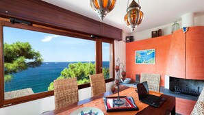 A dining area with a view of the sea, wicker chairs, a wooden table, and a laptop. - Villa Ad Maiora in Massa Lubrense (Massa Lubrense)