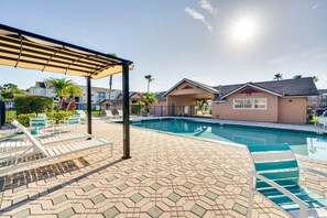 Área da piscina com espreguiçadeiras e um espaço de estar coberto.