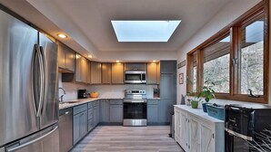 A modern kitchen with stainless steel appliances, a skylight, and a view of the outdoors. - Ski house 8 min from the mountain (Killington)