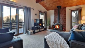 A cozy living room with a fireplace, a TV, and comfortable seating. - Ski house 8 min from the mountain (Killington)
