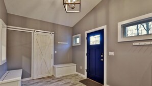 A hallway with a blue door, a white bench, and a wooden floor. - Ski house 8 min from the mountain (Killington)
