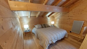 Une chambre confortable dans un chalet en bois, avec un lit, deux lampes de chevet et une petite table.