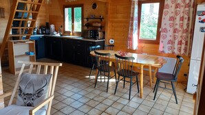 Un intérieur de chalet chaleureux comprenant une cuisine, un coin repas et une chambre à coucher située en mezzanine.